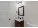 Bathroom with wood vanity, framed mirror, modern lighting, and white door at 2813 Hilliard Dr, Charlotte, NC 28205