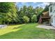 Spacious backyard with a lush lawn, mature trees, a wooden deck, an above-ground pool, and a wooden fence at 3505 Mallard Cove Ct, Charlotte, NC 28269
