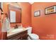 Cozy powder room with an orange wall and an updated vanity and toilet at 3505 Mallard Cove Ct, Charlotte, NC 28269
