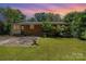 Home's backyard with a patio, small lawn, brick exterior, and twilight sky at 3939 Sheffield Dr, Charlotte, NC 28205