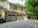 Three-car garage with carriage doors, exterior lights, and a paved driveway at 4001 Doves Roost Ct, Charlotte, NC 28211