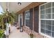 Inviting front porch featuring a brick facade, dark shutters, and decorative potted plants at 5668 Stanfield Ridge Dr, Stanfield, NC 28163