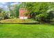 Back exterior of a brick house and backyard lawn featuring mature landscaping at 626 Trail Ridge Rd, Matthews, NC 28105