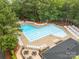 Aerial shot of a large pool with multiple lanes and deck chairs surrounded by mature trees at 626 Trail Ridge Rd, Matthews, NC 28105