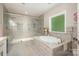 Bright bathroom featuring a separate tub and a glass shower with gray tiling at 8418 Knollwood Cir, Charlotte, NC 28213