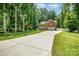Beautiful brick home with a well-manicured lawn, long driveway, and mature trees at 8418 Knollwood Cir, Charlotte, NC 28213