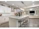 Bright kitchen featuring a large island with bar stool seating and a view of the living room with fireplace at 8418 Knollwood Cir, Charlotte, NC 28213