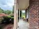 Relaxing covered front porch with brick and painted columns, wicker seating and manicured landscaping at 8620 Rolling Fields Rd, Charlotte, NC 28227
