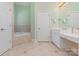 Bright bathroom featuring vanity with sink, linen closet, and tiled bathtub at 9210 Ginhouse Ln, Charlotte, NC 28277