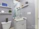 Bathroom features a white vanity, toilet, mirror, and decorative shelving at 9210 Ginhouse Ln, Charlotte, NC 28277