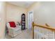 Upstairs hallway features comfortable chair, bookcase, and staircase with wood banister at 9210 Ginhouse Ln, Charlotte, NC 28277