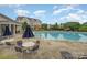 A large sparkling pool is surrounded by tables, chairs, and sun loungers near the clubhouse at 9210 Ginhouse Ln, Charlotte, NC 28277