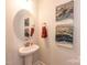 Elegant powder room with a pedestal sink, round mirror, and decorative artwork on the walls at 1090 Gardenia Dr # 5, Mt Ulla, NC 28125