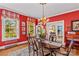 Bright dining room displays red accent walls, traditional decor, windows and hardwood floors at 117 N Mulberry St, Statesville, NC 28677