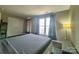 Spacious bedroom featuring a gray bed, wood floors, curtains, and a view of the windows and double closets at 12564 Jessica Pl, Charlotte, NC 28269