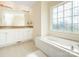 Well-lit bathroom featuring a soaking tub, double sinks, and a decorative window at 1271 Applewood Ln, York, SC 29745