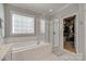 Well-lit bathroom featuring a soaking tub, glass shower, and a walk-in closet at 14727 Brannock Hills Dr, Charlotte, NC 28278