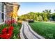 Landscaped backyard with a stone walkway, lush lawn, mature trees and patio dining area at 159 Holly Ridge Dr, Mooresville, NC 28115