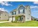 Two-story home with gray and blue siding, stone veneer, covered porch, and landscaped front yard at 16404 Wavenly House Dr, Charlotte, NC 28273