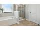 Relaxing bathroom featuring soaking tub with window, tiled shower, and neutral color palette at 1970 Topaz Plz, Davidson, NC 28036