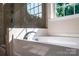 Bright bathroom with a white bathtub beneath a large window offering an outdoor view at 203 Rustling Waters Dr, Mooresville, NC 28117