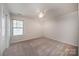 Bedroom features neutral carpet, ceiling fan, and a window providing natural light at 203 Rustling Waters Dr, Mooresville, NC 28117