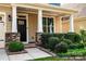 Inviting front porch with stone pillars, manicured bushes, and stylish black front door at 203 Rustling Waters Dr, Mooresville, NC 28117
