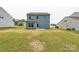 View of the backyard featuring a two-story home with blue siding and a spacious grassy area at 3107 Riker St, Clover, SC 29710