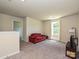 Spacious bonus room featuring neutral carpeting, a red sofa, and natural light from a nearby window at 323 J C Dellinger Rd, Cherryville, NC 28021