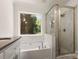 Bright bathroom featuring a tiled shower, tub, and a large window overlooking nature at 3429 Lazy Day Ln, Charlotte, NC 28269