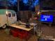 An enchanting backyard scene with a fireplace, camper, and outdoor seating illuminated with ambient lighting at 506 Clement Ave, Charlotte, NC 28204