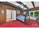 Bedroom featuring wood paneled walls, red carpet, and outdoor views at 514 Wood St, Troy, NC 27371