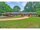 Charming brick home features a well-manicured lawn, mature trees, and a circular driveway, offering classic curb appeal at 514 Wood St, Troy, NC 27371