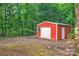 Outbuilding with garage door, side door and small window surrounded by trees, green bushes and grass at 514 Wood St, Troy, NC 27371