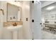 Stylish half-bathroom with a pedestal sink, decorative mirror, and adjacent office space at 5228 Tomsie Efird Ln, Charlotte, NC 28269