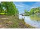 Scenic waterfront view with private dock and covered boat lift, surrounded by lush greenery and clear blue skies at 669 Kenway Loop, Mooresville, NC 28117