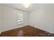 Empty bedroom featuring hardwood floors, white walls, and decorative wainscoting and trim at 6938 Wrentree Dr, Charlotte, NC 28210