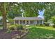 Charming white brick home featuring black shutters, a lush front lawn, and mature trees at 6938 Wrentree Dr, Charlotte, NC 28210