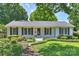 Charming white brick home featuring black shutters, a lush front lawn, and mature trees at 6938 Wrentree Dr, Charlotte, NC 28210