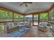 Inviting screened porch with wicker seating, ceiling fan, and wooded backyard views at 6938 Wrentree Dr, Charlotte, NC 28210