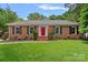 Charming brick ranch with a manicured lawn, red door, and black shutters offers great curb appeal at 6946 Woodstock Dr, Charlotte, NC 28210