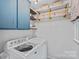 Functional laundry room with modern washer and dryer, along with built-in storage shelves at 6946 Woodstock Dr, Charlotte, NC 28210