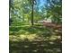 Scenic backyard with mature trees, lush green lawn, and a glimpse of the white house at 695 Knollcrest Ne Dr, Concord, NC 28025