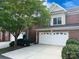 Brick two-story home with a white garage door, mature trees, and manicured landscaping create great curb appeal at 705 Congressional Ln, Fort Mill, SC 29708