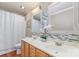 Well-lit bathroom featuring double sinks with decorative mirrors and a shower with a curtain at 7121 Bidford Ct, Indian Land, SC 29707