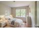 A bright bedroom showcases a white bed, neutral decor, and a large window overlooking the yard at 7320 Ritter Dr, Charlotte, NC 28270