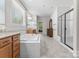 Bright bathroom featuring a soaking tub, tiled shower, and wood cabinets at 7798 Sand Trap Ln, Stanley, NC 28164