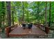 Outdoor dining deck surrounded by mature trees, perfect for enjoying meals in a natural setting at 7798 Sand Trap Ln, Stanley, NC 28164