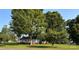 This is an exterior shot of the home with mature trees on a well-manicured lawn at 100 S Rudisill Ave, Cherryville, NC 28021