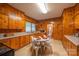 A rustic kitchen with wood-paneled walls, cabinets, and a cozy breakfast nook with a round table and chairs at 100 S Rudisill Ave, Cherryville, NC 28021